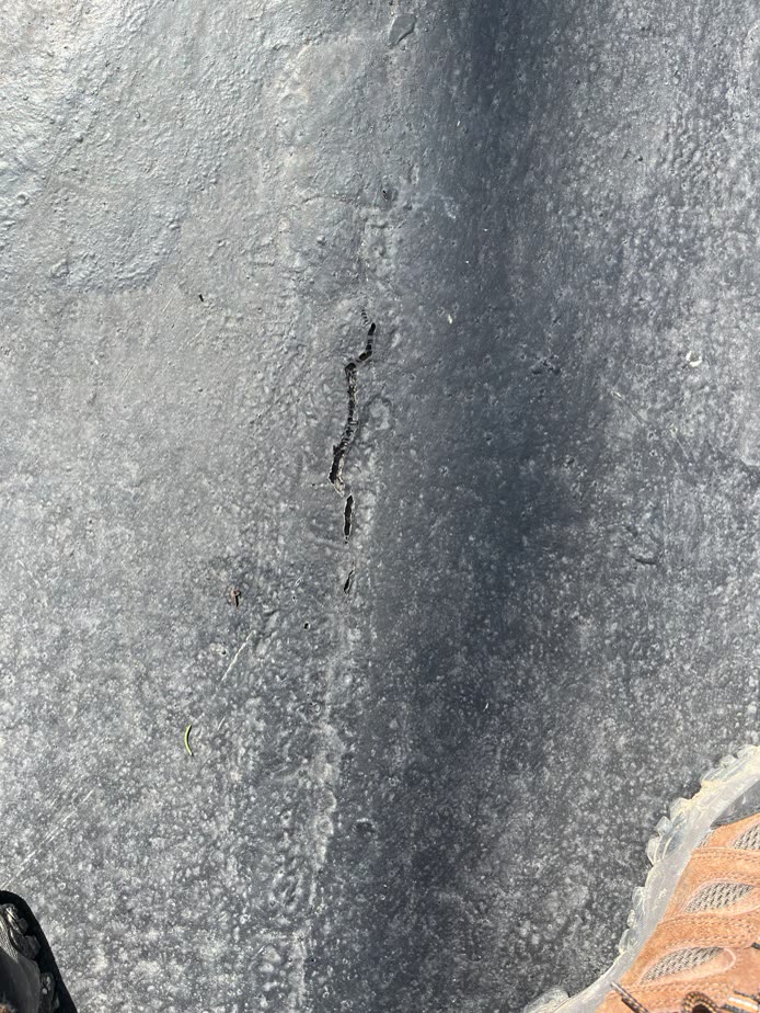 Open crack across flat roof membrane surface, Winnetka stone home